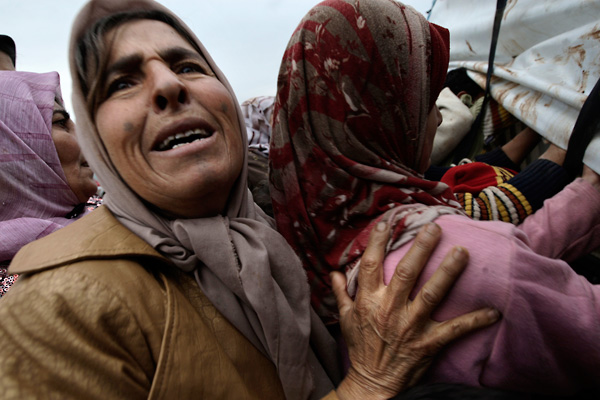 Syrian women receive pillows and blankets at a tent camp for internally displaced people in the village of Atmeh, where some of the hundreds of thousands of Syrians uprooted by the country's brutal civil war are sheltering.